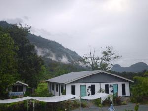 a small white building with a mountain in the background at Belibis Yard in Kampar
