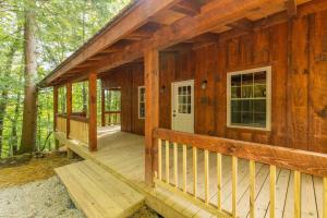 a wooden cabin with a porch in the woods at Pet-Friendly Tiny Cabin - Pine Point in Pine Ridge