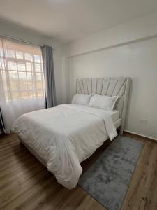 a bedroom with a large white bed with a window at Savannah Residence in Libwezi