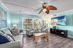 a living room with a couch and a ceiling fan at Plumbago - 5251C in Siesta Key