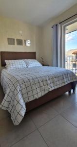 un grand lit dans une chambre avec une grande fenêtre dans l'établissement Habitación Alta California con Alberca y Coto privado, à Tlajomulco de Zúñiga