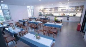 唐山市にあるGreenTree Inn Tangshan Nanhu International Exhibition Centerの青いテーブルと椅子と人が置かれたレストラン