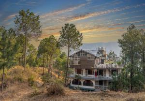 a house in the middle of a field with trees at Luxury Kasauli Skyline 2BHK Apartment with Jacuzzi and Mountain View in Kasauli