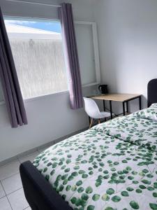 a bedroom with a bed and a table and a window at Chambres chez l'habitant in Saint-Paul