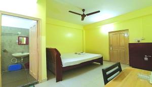 a room with a bed and a bathroom with a ceiling fan at Hotel Avisha in Kolkata +23 photos
