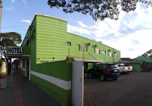 a green building with a car parked in a parking lot at Hotel Figueira Palace in Dourados