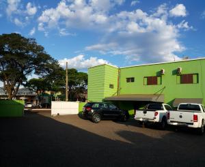 two cars parked in front of a green building at Hotel Figueira Palace in Dourados