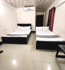 two beds in a small room with at W Hotel Sylhet in Sylhet