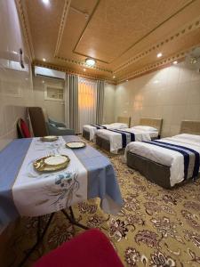 a hotel room with three beds and a table at دار اليقين in Al Madinah