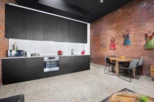 The Radford on Elizabeth في Geelong West: مطبخ بدولاب سوداء وطاولة وجدار من الطوب