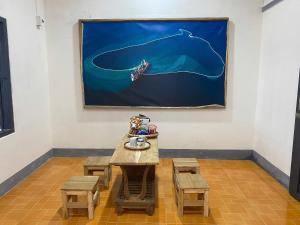 a table with benches and a painting on the wall at Homestay Nhà Của Gạo in Ấp Thiẹn Ái