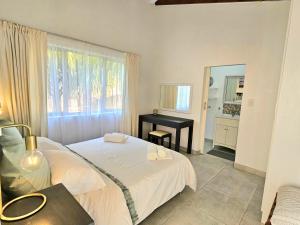 a bedroom with a bed and a desk and a window at ONE on Michelle in Ballito