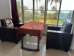 a table with a red blanket on it with two chairs at water front guest house in Arambol