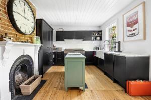 een keuken met zwarte kasten en een grote klok aan de muur bij Gable House Geelong in Geelong