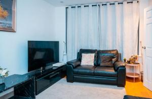 a living room with a leather couch and a television at Cozy room 1 in Sale