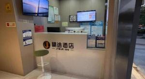 a store with a counter with two monitors on the wall at JTOUR Inn Wuhan Textile University in Wuhan