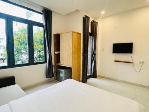 a bedroom with a bed and a tv and window at Bona Hostel in Da Nang