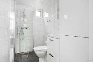 a white bathroom with a toilet and a shower at First Camp Vadstena - Vättern in Vadstena