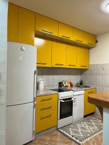 a kitchen with yellow cabinets and a white refrigerator at Stan na dan Kalin in Bugojno