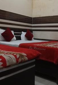 two beds with red and white pillows in a room at New Gaytri Place Near by Prem Mandir in Jāmb