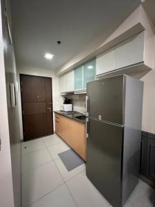 a kitchen with a stainless steel refrigerator and wooden cabinets at 1BR - Uptown BGC Taguig in Manila