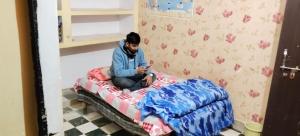 a woman sitting on a bed looking at her cell phone at Rk home stay in Jhūsi