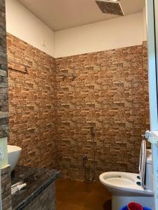 La salle de bains est pourvue de toilettes et d'un mur en briques. dans l'établissement Hotel Sun Star International Pvt Ltd, à Siddharthanagar
