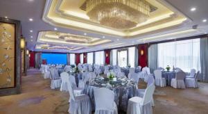 a banquet hall with white tables and white chairs at Feicheng Blossom Hotel in Feicheng