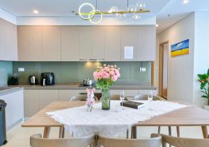 a dining room table with pink flowers in a vase at Căn Hộ The Sóng Mới Nhất Gần Biển - Condotel Seaside Vung Tau Homestay in Vung Tau +79 photos