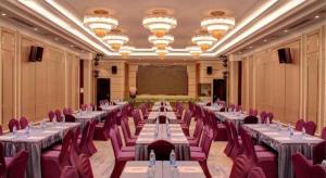 a banquet hall with tables and chairs and a projection screen at Huayu Zhidi Hotel in Zhongshan