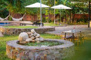 a fountain in a yard with tables and umbrellas at Sun Hostel and Restaurant Kampot in Kampot