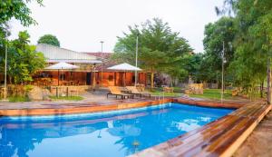 a swimming pool in a yard with tables and umbrellas at Sun Hostel and Restaurant Kampot in Kampot