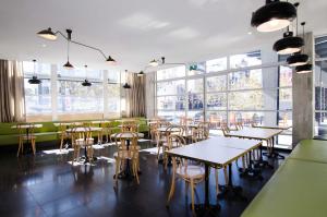 a restaurant with tables and chairs and windows at ibis budget Sydney East in Sydney