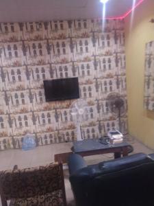 a living room with a wall with a tv and a table at Ensuite in Ejigbo
