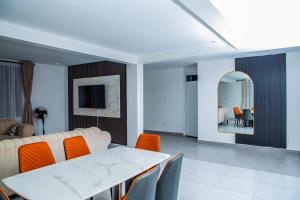 KibosZikora Villa Kisumu的客厅配有白色桌子和橙色椅子