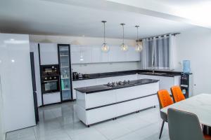 KibosZikora Villa Kisumu的厨房配有白色橱柜、橙色椅子和桌子