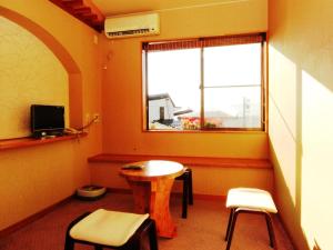 ein Zimmer mit einem Tisch, zwei Stühlen und einem Fenster in der Unterkunft Ikemoto in Nozawa Onsen
