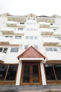 Un edificio de apartamentos alto y blanco con una puerta de madera. en Fah Place Hotel, en Nan