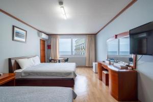 ein Hotelzimmer mit zwei Betten und einem Flachbildfernseher in der Unterkunft Gangneung Gyeongpodae Gangneung Motel in Kangmun + 165 Fotos