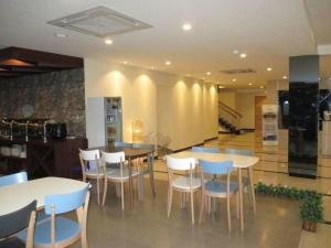 a dining room with tables and white chairs at Nite and Day Batam Jodoh Square in Tanjunguma