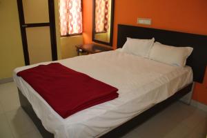 a white bed with a red blanket on it at Arunachala Residency in Tiruvannāmalai