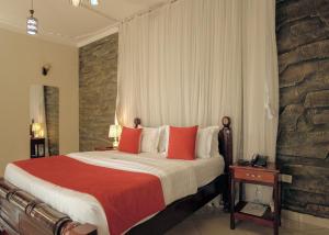 ein Schlafzimmer mit einem großen Bett mit roten Kissen in der Unterkunft Nile Bridge Cottages in Jinja
