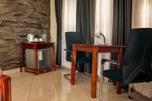 a room with chairs and a table and a tv at Nile Bridge Cottages in Jinja