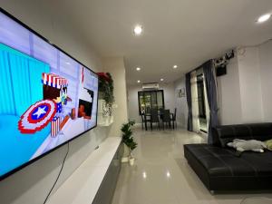 Una sala de estar con un televisor grande y un sofá. en บ้านเดี่ยวหางดง ย่านมหาวิทยาลัยนอร์ทเชียงใหม่, en Ban Phae Buak Ha 9 fotos más