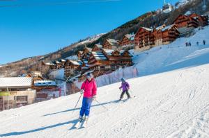 two people skiing down a snow covered ski slope at Résidence Goélia Les Chalets Valoria in Valloire