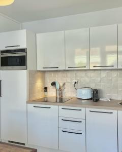 a white kitchen with white cabinets and a sink at Le Refuge du Port in Étaples