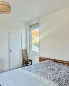 a bedroom with a bed and a window and a chair at Le Refuge du Port in Étaples