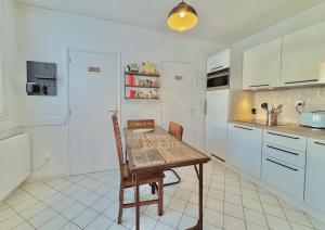 a kitchen with a wooden table and white cabinets at Le Refuge du Port in Étaples +6 photos