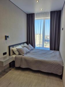 a bedroom with a bed and a large window at Апартаменти на Марсельській 62 в ЖК Острова, 1 спальня та кухня-студія in Odesa