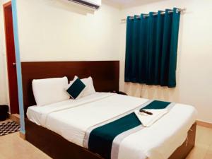 a bedroom with a large bed with a blue curtain at At Home Hotel Darbar in Hyderabad +8 photos